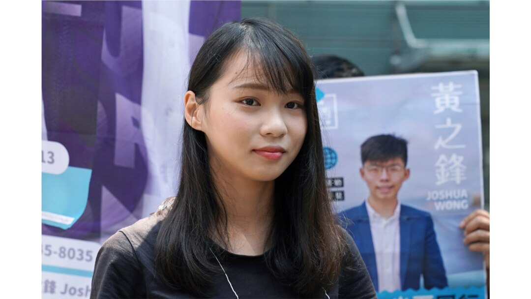 In this Sept. 28, 2019, photo, Hong Kong pro-democracy activist Agnes Chow stands next to a poster of activist Joshua Wong, in Hong Kong.