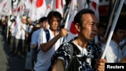 Members of the nationalist movement "Ganbare Nippon" holding Japanese national flags march while paying tribute to the war dead near Yasukuni Shrine in Tokyo, August 15, 2013, on the 68th anniversary of Japan's surrender in World War II.
