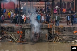A man pushes cremated remains into the Bagmati River at the Pashupatinath Temple in Kathmandu, Nepal, Saturday, May 28, 2022. The temple was declared a World Heritage Site by UNESCO in 1979. (AP Photo/Niranjan Shrestha)