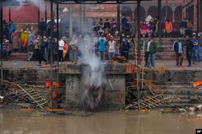 A man pushes cremated remains into the Bagmati River at the Pashupatinath Temple in Kathmandu, Nepal, Saturday, May 28, 2022. The temple was declared a World Heritage Site by UNESCO in 1979. (AP Photo/Niranjan Shrestha)