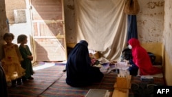 FILE - A nurse, right, registers a patient at a mobile clinic set up at the residence of a local elder in Yarmuhamad village, near Lashkar Gah in Helmand province, March 28, 2021.