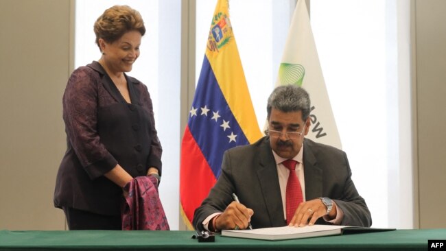Fotografía difundida por el despacho del presidente venezolano, Nicolás Maduro, mientras firma el libro de visitantes distinguidos del Nuevo Banco de Desarrollo de los BRICS, en presencia de Dilma Rousseff, en Shanghái, China, el 10 de septiembre de 2023.