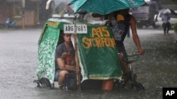 A Filipino man and his dog ride a pedicab along a flooded road in suburban Mandaluyong, east of Manila, Philippines, as monsoon downpours intensify while Typhoon Nepartak exits the country on Friday, July 8, 2016. 