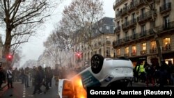 Prevrnuti automobil gori za vreme protesta "žutih prsluka" na bulevaru Sen Žermen u Parizu, 5. januara 2019.