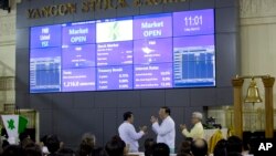 Serge Pun, far right executive chairman of First Myanmar Investment Maung Maung Thein, center Deputy Minister of Finance and Revenue applued after ringing the bell to commence electronic trading during the opening day of trading at Yangon Stock Exchange in Yangon, Myanmar, March 25, 2016.