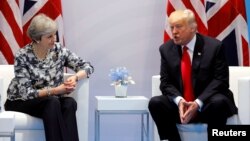 La primera ministra británicia, Theresa May, conversa con el presidente estadounidense, Donald Trump, durante la cumbre del G-20 en Hamburgo, Alemania, el 8 de julio de 2017.
