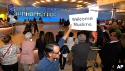 Un hombre muestra un cartel de bienvenida a los musulmanes en el Aeropuerto Internacional Tom Bradley de Los Ángeles, el jueves 29 de junio.