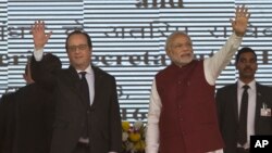 French President Francois Hollande, left, and Indian Prime Minister Narendra Modi wave at the audience as they arrive for the foundation stone laying for the headquarters of the International Solar Allliance at Gurgaon, outskirts of New Delhi, Jan. 25, 2016.