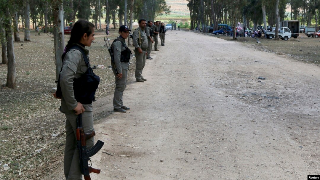 FILE - Kurdish Democratic Union Party (PYD) members stand guard during a Labour Day celebration in Efrin, Syria, May 1, 2014.