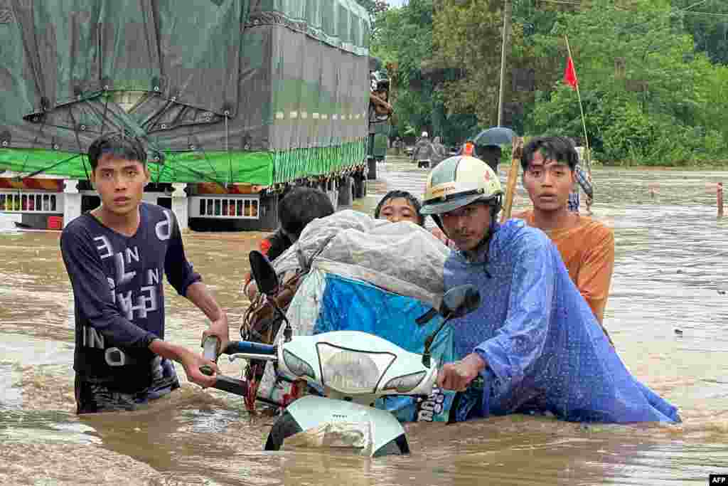 People walk through flood waters in Thagaya in Myanmar&#39;s Bago region following heavy rains in the aftermath of Typhoon Yagi.