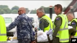 In this image made from video, an injured tourist in the volcano eruption is carried to an Australian Air Force plane in Hamilton, New Zealand, Dec. 12, 2019. 