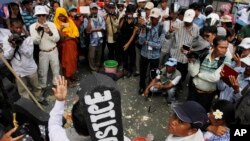 An activist of Cambodian National Rescue Party Meach Sovannara, lower center, gives a speech as surrounded by local journalists at a blocked main street near the Phnom Penh Municipality Court during a gathering to call for the release of anti-government p