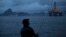 FILE - A man fishes in Guanabara Bay where an oil platform floats, backdropped by Sugar Loaf Mountain, left, in Niteroi, Brazil, April 21, 2015.