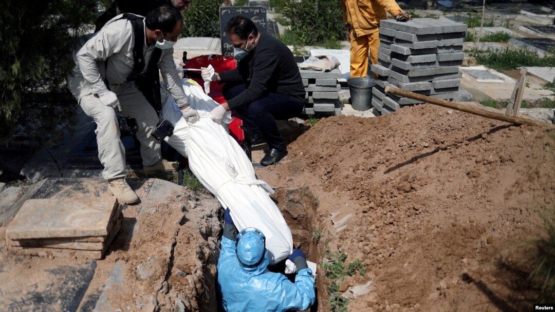 Iranian men bury the journalist Abdollah Zavieh, who passed away due to coronavirus disease (COVID-19), at Behesht Zahra cemetery in Tehran, March 24, 2020.
