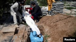 Iranian men bury the journalist Abdollah Zavieh, who passed away due to coronavirus disease (COVID-19), at Behesht Zahra cemetery in Tehran, March 24, 2020.