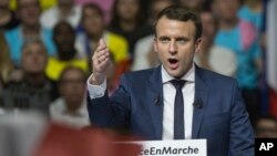 Supporters of French presidential candidate Emmanuel Macron hold placards as he speaks during a campagin rally in Lyon, central France, Feb. 4, 2017.