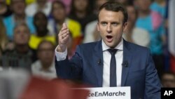 FILE - Supporters of French presidential candidate Emmanuel Macron hold placards as he speaks during a campagin rally in Lyon, central France, Feb. 4, 2017.