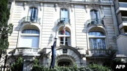 A man cleans the surveillance camera in the grounds of the Iranian Embassy in Paris, Sept. 14, 2018, after people taking part in a demonstration in a nearby street split off and walked to the embassy, where they sprayed red paint on the embassy sign and trashed computers that had been placed outside the embassy grounds for collection.