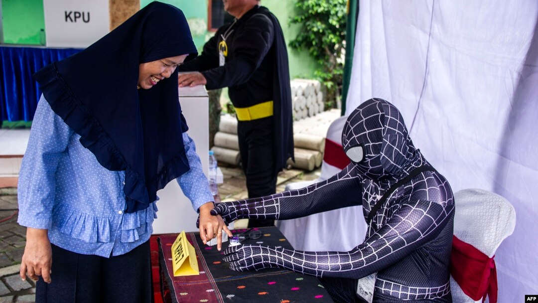 Indonesian election workers dressed in superhero costumes register voters at a polling station in Surabaya, April 17, 2019.