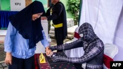 Indonesian election workers dressed in superhero costumes register voters at a polling station in Surabaya, April 17, 2019.