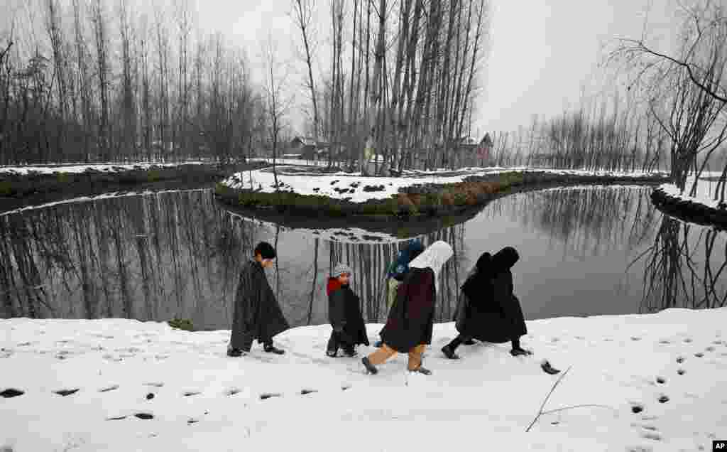 Anak-anak Kashmir berjalan di atas jalanan bersalju di kota Srinagar, India.