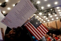 FILE - New citizens stand during a U.S. Citizenship and Immigration Services (USCIS) naturalization ceremony in Manhattan, New York, April 10, 2017.