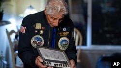 El veterano de la Marina Bob Fernández sostiene una fotografía del USS Curtiss, en el que sirvió durante el ataque a Pearl Harbor, el martes 19 de noviembre de 2024, en Lodi, California (Foto AP/Godofredo A. Vásquez)