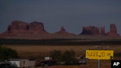 Tanda kawasan Navajo Drive, dengan Sentinel Mesa, rumah dan bangunan lain di Oljato-Monument Valley, Utah, terlihat dari kejauhan, 30 April 2020. (Foto: dok)