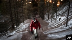 A migrant from Guinea headed to France treks into the mountains by the Italian border town of Claviere in an attempt to cross the border undetected at night, Saturday, Dec. 11, 2021.