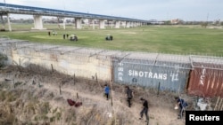 Los migrantes caminan a orillas del río Grande para encontrar una manera de ingresar a EEUU, en Eagle Pass, Texas, el 27 de febrero de 2024. REUTERS/Go Nakamura