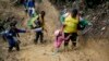 Una mujer tira de una niña para sacarla del lodo mientras migrantes ecuatorianos atraviesan el Darién desde Colombia hasta Panamá con la esperanza de llegar a Estados Unidos el sábado 15 de octubre de 2022.