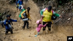 Una mujer tira de una niña para sacarla del lodo mientras migrantes ecuatorianos atraviesan el Darién desde Colombia hasta Panamá con la esperanza de llegar a Estados Unidos el sábado 15 de octubre de 2022.