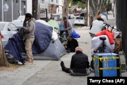 Homeless people gather with their belongings and tents in the Mission District, Tuesday, Sept. 10, 2024, in San Francisco. (AP Photo/Terry Chea)