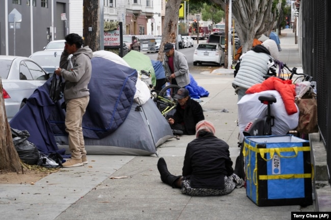 Homeless people gather with their belongings and tents in the Mission District, Tuesday, Sept. 10, 2024, in San Francisco. (AP Photo/Terry Chea)