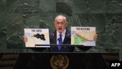 O primeiro-ministro israelita, Benjamin Netanyahu, segura mapas enquanto discursa durante a 79.ª sessão da Assembleia Geral das Nações Unidas, na sede das Nações Unidas em Nova Iorque, a 27 de setembro de 2024.