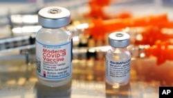 FILE - In this Feb. 25, 2021, file photo, vials for the Moderna and Pfizer COVID-19 vaccines are displayed on a tray at a clinic set up by the New Hampshire National Guard in the parking lot of Exeter, N.H., High School. The nation is poised to get…