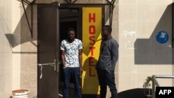 Sodiq Olamilekan, left, a 25-year-old Nigerian, stands next to his 21-year-old brother, Ismail, at a door of a hostel in Moscow, July 12, 2018.