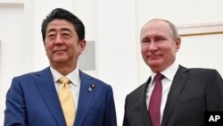 Presiden Rusia Vladimir Putin (kanan) dan PM Jepang Shinzo Abe berjabat tangan sebelum berlangsunya pembicaraan terkait sengketa wilayah di Kremlin, Moskow, Rusia, 22 Januari 2019. 