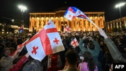 Georgian pro-democracy groups activists wave flags of Georgia as they protest against a repressive "foreign influence" bill outside the parliament in Tbilisi on April 15, 2024.