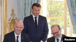 French president Emmanuel Macron stands during the signature of an agreement between FIFA president Gianni Infantino and AFD (French Development Agency) president Remy Rioux at the Elysee Palace, in Paris, June 4, 2019. 