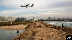 Israelis fish in the Mediterranean sea as aircraft prepares to land in Sde Dov airport in Tel Aviv, Nov. 24, 2013. 