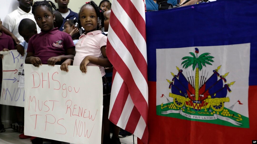 Children stand next to United States and Haitian flags as they hold signs in support of renewing TPS for immigrants from Central America and Haiti now living in the United States, during a news conference, Nov. 6, 2017, in Miami.