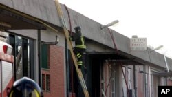 A firefighter climbs a ladder to get to the roof of a Chinese-run garment factory where fire swept through on Sunday, in Prato, near Florence, Italy, Dec. 1, 2013.