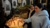 A Syrian Christian woman lights a candle during the first Sunday Mass since Syrian President Bashar al-Assad's ouster, at Mariamiya Orthodox Church in Old Damascus, Syria, Dec. 15, 2024.