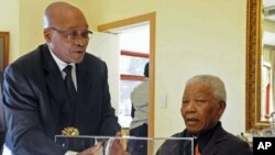 South African President Jacob Zuma presents former President Nelson Mandela with a gift - an architect's rendering of the Nelson Mandela Legacy Bridge - (file photo)