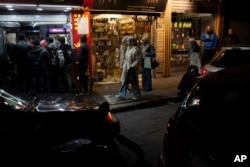 People walk past shops on a street in the Bab Touma neighborhood of the Old City of Damascus, Syria, Dec. 14, 2024.