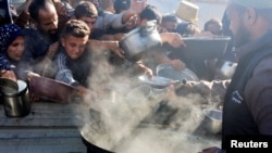 Orang-orang Palestina menerima bantuan makanan di Khan Younis, di bagian selatan Jalur Gaza, 4 Desember 2024. (Foto: Mohammed Salem/Reuters)