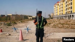资料照片:一名中国警察守在新疆伊宁一处官方所说的职业技能教育培训中心外的路口。(2018年9月4日)