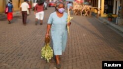 Una mujer camina hacia la procesión del Domingo de Ramos en medio de la cuarentena por el COVID-19 en Nahuizalco, El Salvador, el 5 de abril de 2020.