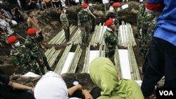 Tentara Indonesia berdiri di antara jenazah korban letusan gunung Merapi di Umbulharjo, Yogyakarta, Indonesia.